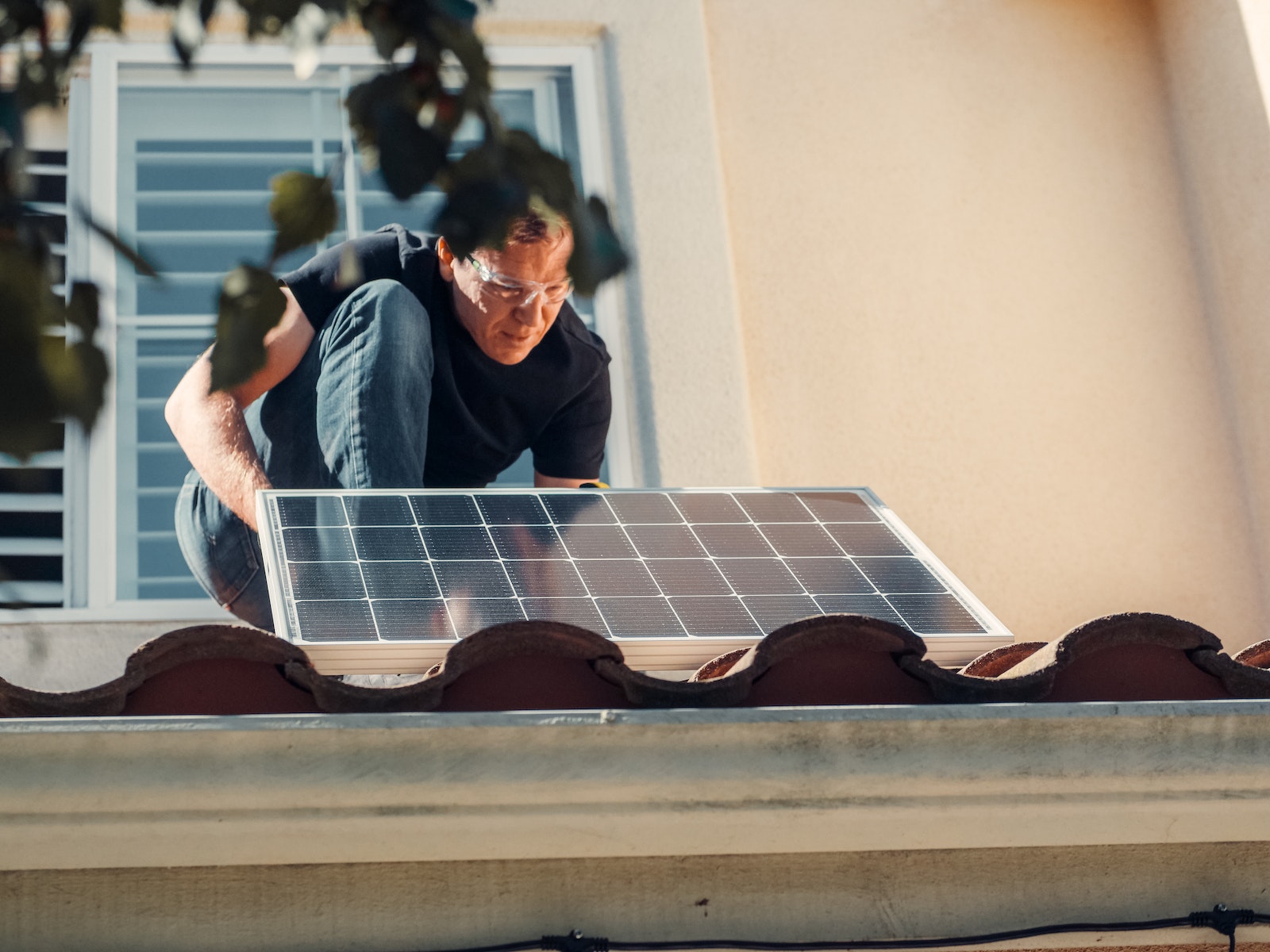 Un hombre con camisa negra instalando un panel solar en el techo