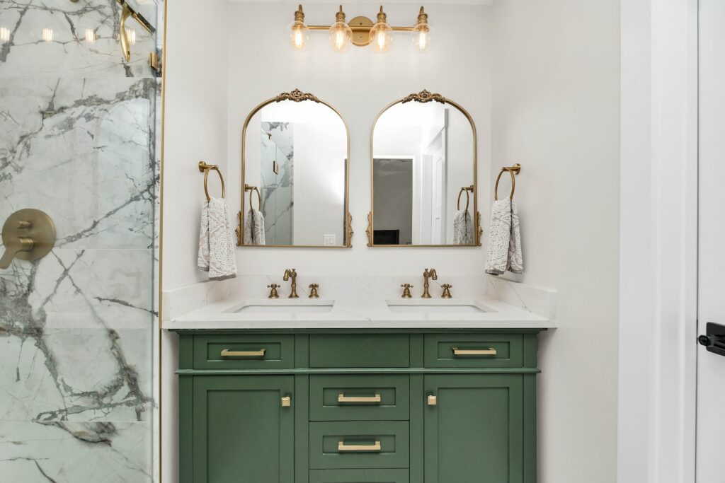 a bathroom with marble counter tops and green cabinets
